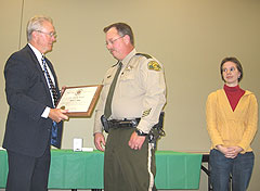 Deputy Perry Ghee receives award from Sheriff Dennis Anderson as Sarah Elrod looks on.