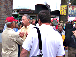 Iowa Senator Chuck Grassley (yellow shirt) talks with people outside the cattle barn at the Iowa State Fair.